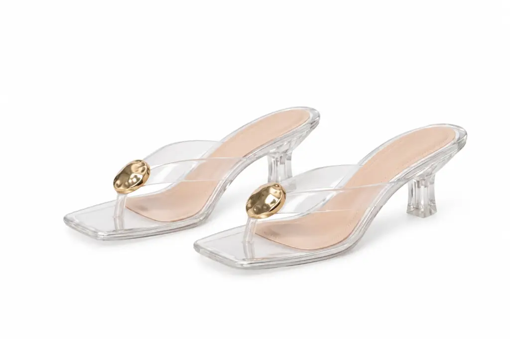 Sandalias transparentes con adorno dorado.webp
